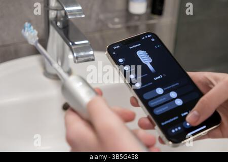 Using a smartphone app to control and manage settings on an electric toothbrush, hands demonstrate advanced personal oral hygiene management through i Stock Photo