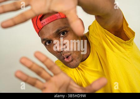 Young man wearing a red cap and a yellow t-shirt is making a frame with his hands Stock Photo
