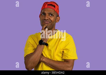 Studio portrait of a thoughtful young man wearing casual clothes and looking away against purple background Stock Photo