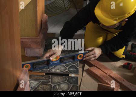 While laying the terracotta, the general construction worker checks the correctness of execution with a spirit level. An employee wearing personal pro Stock Photo
