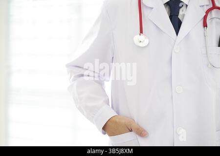 Unknown doctor posing hand in pocket in the office, he is wearing a stethoscope Stock Photo
