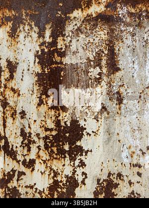 Vertical close-up of rusty metal surface with peeling paint and corrosion marks. Abstract industrial texture, weathered material, no people. Stock Photo