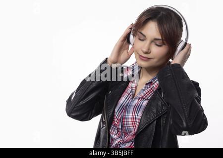 A stylish young woman wearing headphones, deeply immersed in music, effortlessly exuding contemporary modern vibes Stock Photo
