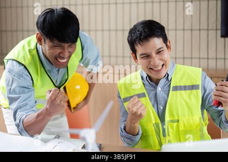 Green tech engineers celebrating the success of a wind energy project Stock Photo