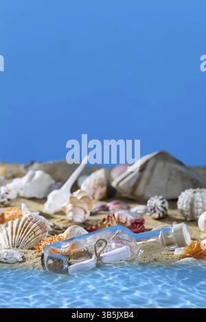 A glass bottle with a letter washed up on the beach shore. Sea beach full of shells and sand. Blue sky. Clean water Stock Photo