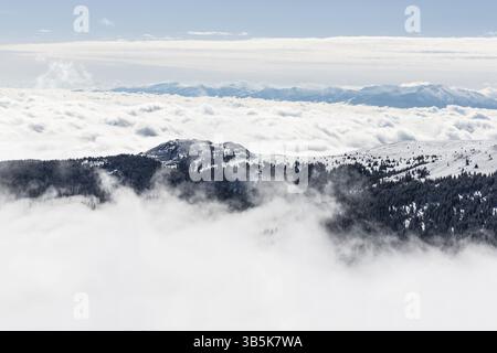 A rocky peak of Vitosha mountain covered with snow and fog. View against the cloudy sky Stock Photo