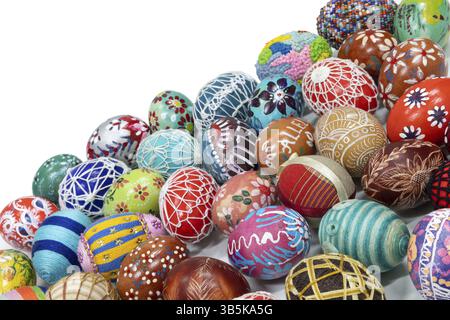 Easter eggs made in different technologies and arranged on a white background in rather random places. A large number of colorful eggs lying side by s Stock Photo
