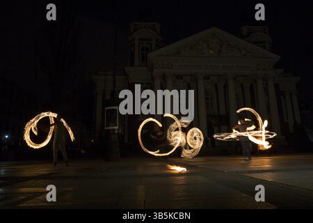 Performers are spinning torches while performing a fire show at night celebrating the international Earth hour event in Sofia, Bulgaria. Long exposure Stock Photo