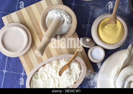 Various ingredients in woodwork dishes. Cereals, wheat, salt, and other ingredients visible with pie on the wooden plate ready for baking Stock Photo
