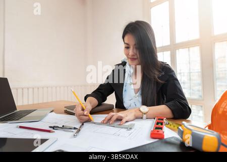 Female architect working on blueprint architects project in office. Stock Photo