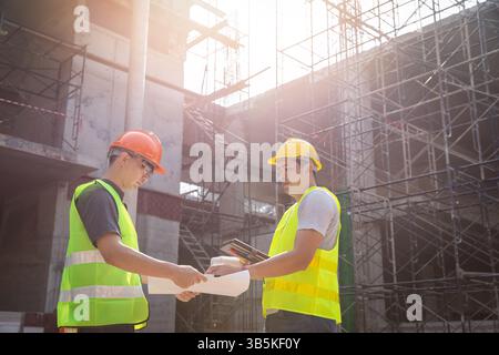 Engineer discussing with foreman about project in building construction site. Stock Photo