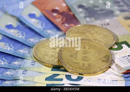 Virtual cryptocurrency money Bitcoin golden coins on European Union EU Euro 5, 10 and 20 banknotes Stock Photo