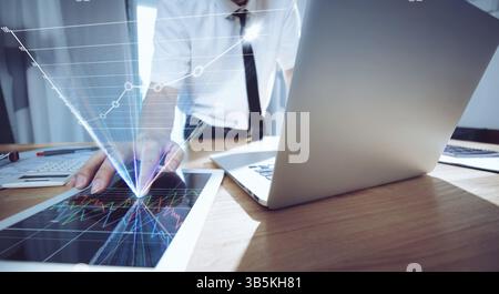 Businessman using laptop and digital tablet to analyse sales report, virtual screen show report chart from digital tablet Stock Photo