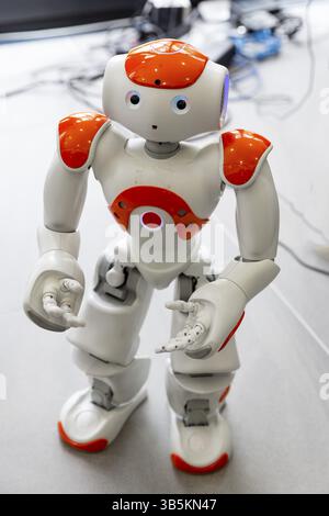 A small robot with human face and body - humanoid. Artificial Intelligence - AI. Orange robot Stock Photo