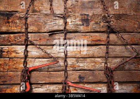 Old wooden blocks are stacked on top of each other and pressed vertically with rusty chains. Stock Photo