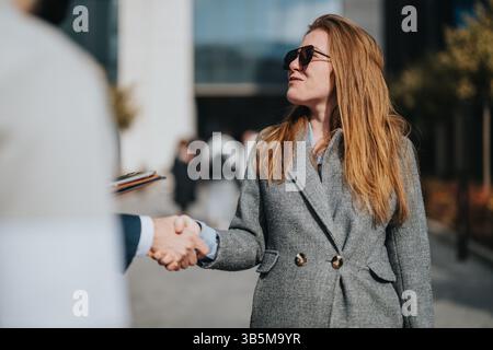 Professional handshake between two individuals outside a modern commercial building Stock Photo