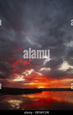A stunning sunset with vibrant colors reflecting on calm waters, perfect for naturethemed aesthetics Stock Photo