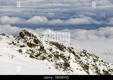 A rocky peak of Vitosha mountain covered with snow. View against the cloudy sky above Bulgaria's capital Sofia Stock Photo