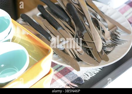 Washed knifes and forks on the ceramic plate, prepared for home celebration Stock Photo