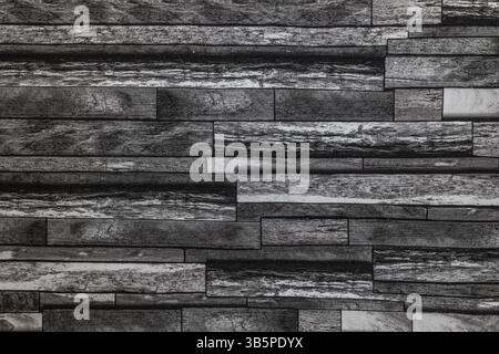 Dark stacked stone wall covering texture for modern and rustic interior design backgrounds Stock Photo