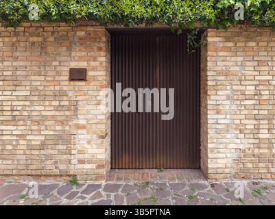 Corrugated Metal Door Set in Brick Wall with Ivy Stock Photo