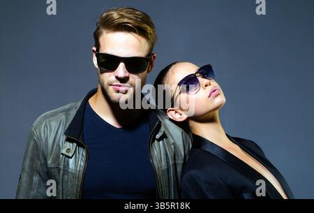 Fashion couple wearing sunglasses. Stylish man and woman with sunglasses posing in studio. Young friends in fashion shoot. Fashion portrait of youth Stock Photo