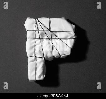 wrapped letter P in white fabric with black string on black background, top view Stock Photo