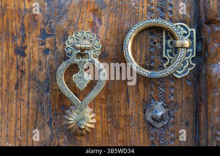 Close-up of a traditional wood carved door with intricately decorated brass fittings in Bukhara, Uzbekistan Stock Photo