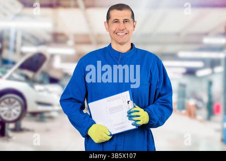 Happy mature mechanic. Portrait of confident mature mechanic in overalls with clipboard at factory Stock Photo
