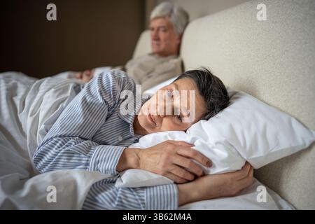 Rejected distressed wife turning away from husband in bed, emotional