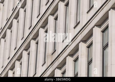 A modernist facade with repeating vertical concrete elements, creating rhythmic patterns and dynamic diagonal shadows. Architecture details. Stock Photo