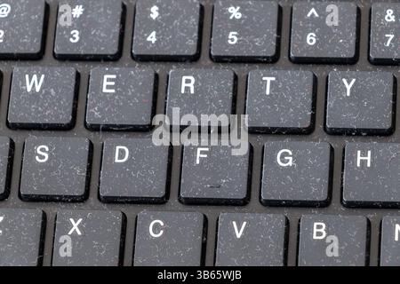 A close-up of a dusty black keyboard, with visible lint and debris accumulated between the keys. Stock Photo