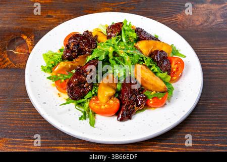 A vibrant salad featuring crisp greens, juicy tomatoes, and savory toppings. Served on a speckled plate against a rustic wooden backdrop, ideal for a Stock Photo
