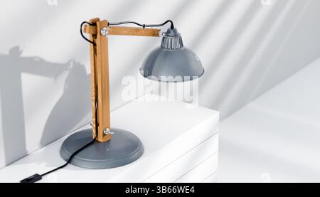 Retro or vintage style desk lamp, classic wooden arm with metal base and grey colored canopy, against white background, isolated. Stock Photo