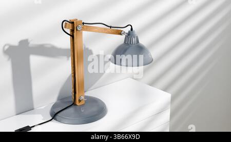Retro or vintage style desk lamp, classic wooden arm with metal base and grey colored canopy, against white background, isolated. Stock Photo
