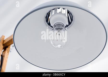 Lamp shade, close-up of the bulb. Retro or vintage style desk lamp,classic wooden arm with metal base and grey colored canopy,against white background Stock Photo