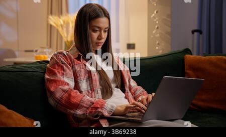 Home studying e-learning using laptop Caucasian teen girl student businesswoman freelancer on couch female woman teenager concentrated working Stock Photo