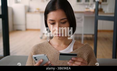 Caucasian hispanic woman girl female online shopping money pay credit card order food delivery home kitchen lady using mobile phone bank app internet Stock Photo