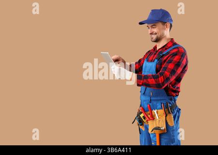 Male technician using tablet computer on beige background Stock Photo