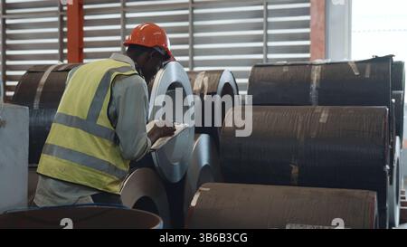 Two black workers engineer factory textile inspection and checking inventory levels of goods of roll Stock Photo