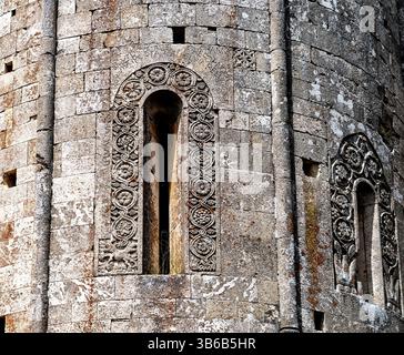 Close-up of ancient stone architecture featuring intricately carved window frames and textured stone walls, showcasing historical craftsmanship and de Stock Photo