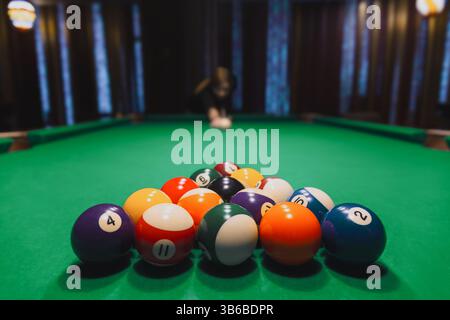 Billiard balls racked on green felt with a player in the background ready to break. Stock Photo