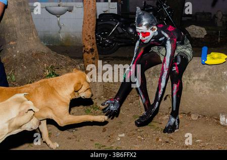 February 15, 2023, Dhaka, , Bangladesh : A student dressed as a ghost plays with dogs during the ghost festival at the University of Dhaka (DU), Bangladesh on February 15, 2023. Ghost festival started around 15 years ago by the students of Shahnewaz Hall, University of Dhaka (as a fun to counter the concept of Valentine’s Day). Students from all departments but mostly the Department of Fine Arts arrange this event on 15th February each year. During this satirical event, students from the Shahnewaz Hall painted and dressed up as different unique, and strange characters and ghosts and decorated Stock Photo