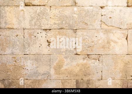Rectangular blocks of beige limestone forming an old weathered wall Stock Photo