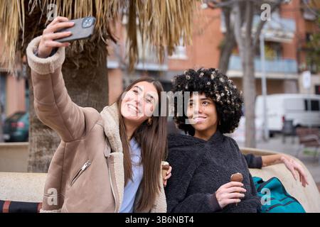 University students taking selfie while eating ice cream outdoors Stock Photo