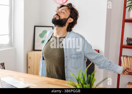 Hipster young man doing a stretching exercise while taking a break from work Stock Photo