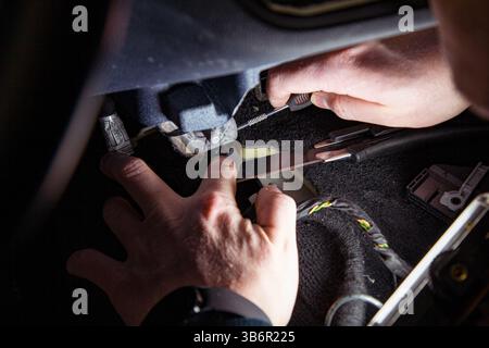 An auto mechanic disassembles a car interior using various trim removal tools and other instruments Stock Photo