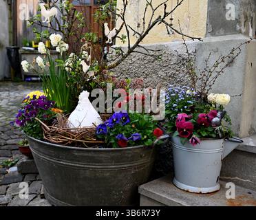 beautiful floral Easter decorations in an old tin vessel filled with spring flowers, branches and a porcelain hen Stock Photo