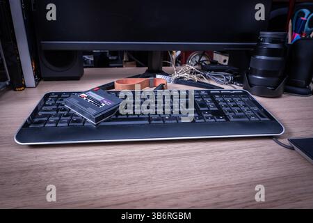Vintage data cartridge resting on contemporary keyboard, highlighting technological progression through contrasting storage mediums Stock Photo