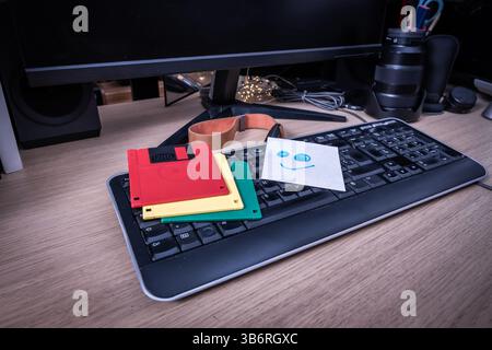 Colorful floppy disks and a smiley note lying on a retro keyboard, evoking vintage technology and memories of the past Stock Photo